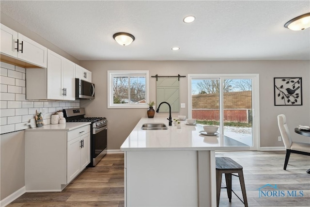 kitchen with white cabinets, appliances with stainless steel finishes, light hardwood / wood-style floors, and sink