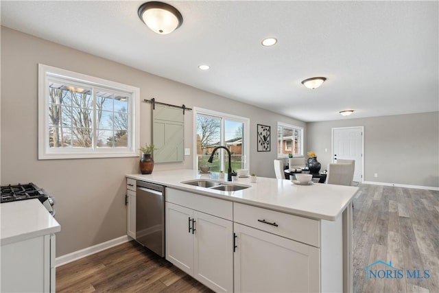 kitchen featuring kitchen peninsula, dark hardwood / wood-style flooring, stainless steel appliances, sink, and a barn door