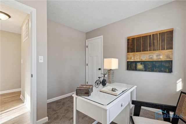 carpeted office with a textured ceiling