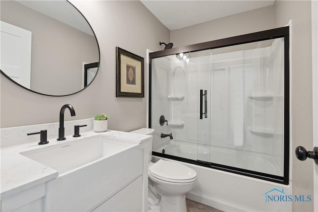 full bathroom with hardwood / wood-style flooring, vanity, toilet, and bath / shower combo with glass door