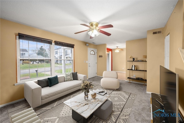 carpeted living room with ceiling fan and a textured ceiling