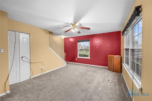 carpeted empty room with ceiling fan and a textured ceiling