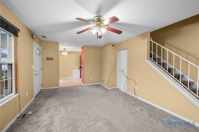 carpeted spare room featuring ceiling fan and a textured ceiling