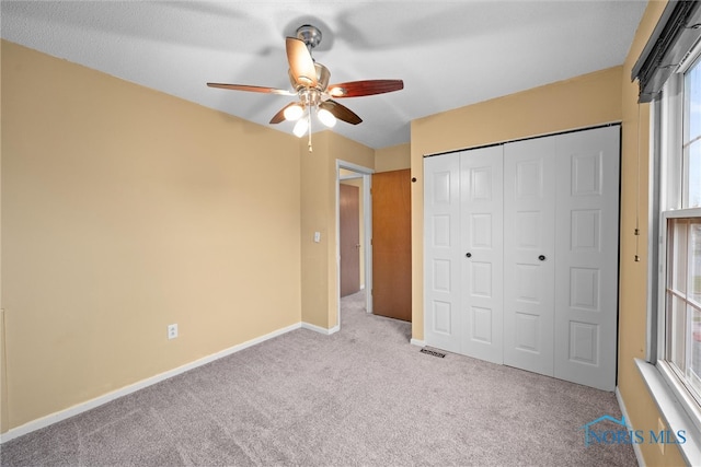 unfurnished bedroom featuring ceiling fan, a closet, and light carpet