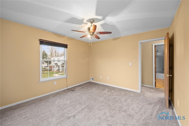 empty room with light carpet, ceiling fan, and a textured ceiling