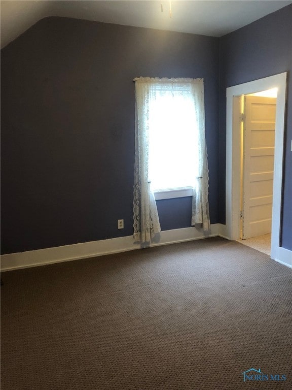 empty room featuring lofted ceiling and carpet floors