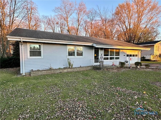 single story home featuring a porch, a garage, and a front lawn