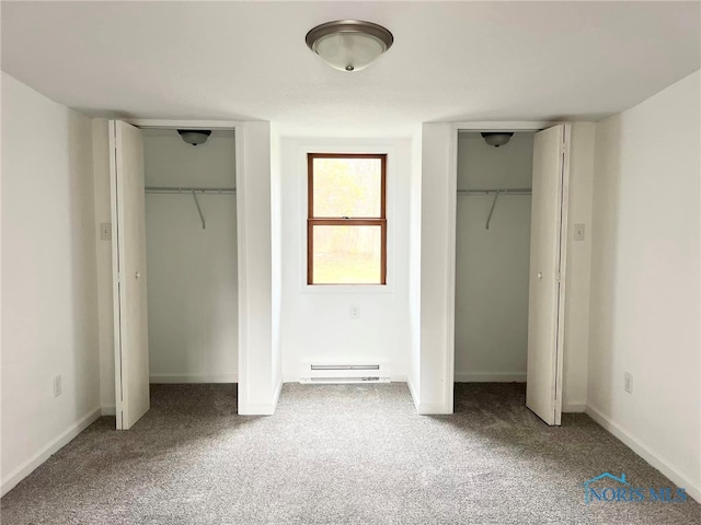 unfurnished bedroom with carpet floors, baseboard heating, and two closets