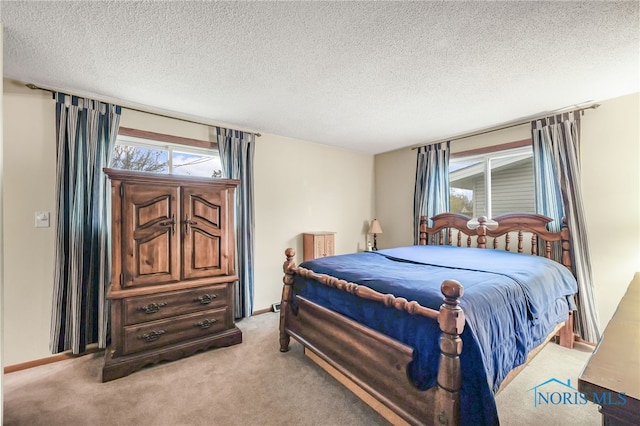 bedroom with light colored carpet, a textured ceiling, and multiple windows