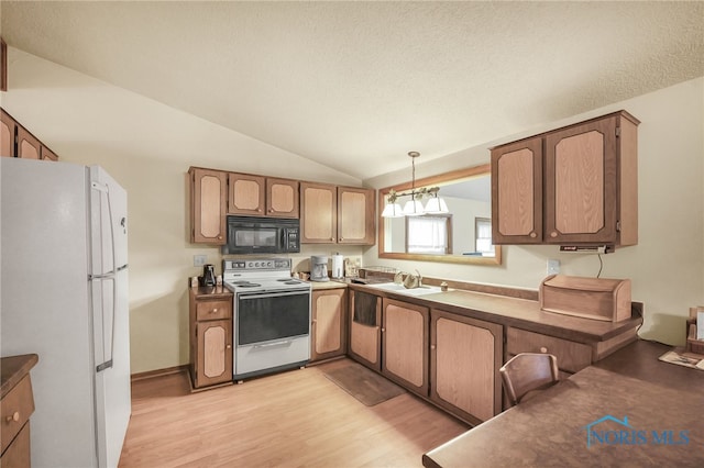 kitchen featuring lofted ceiling, white appliances, sink, decorative light fixtures, and light hardwood / wood-style floors