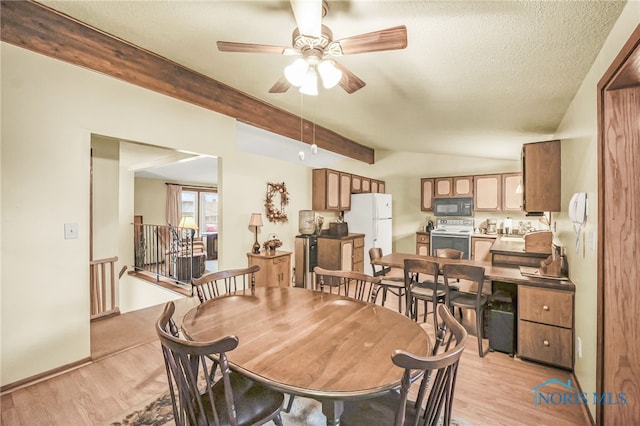 dining space featuring vaulted ceiling with beams, ceiling fan, light hardwood / wood-style floors, and a textured ceiling