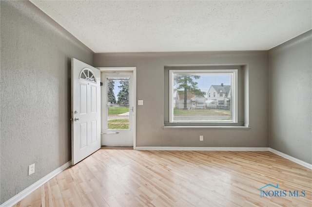 foyer entrance featuring a healthy amount of sunlight, a textured ceiling, and light hardwood / wood-style floors