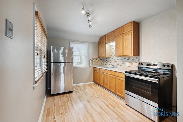 kitchen with light wood-type flooring, sink, appliances with stainless steel finishes, and tasteful backsplash