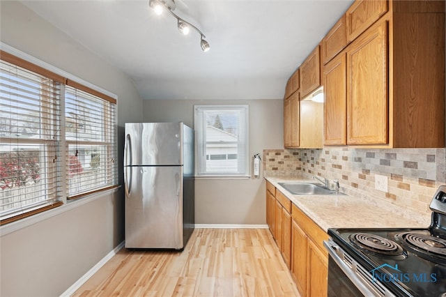 kitchen featuring backsplash, sink, light wood-type flooring, and appliances with stainless steel finishes