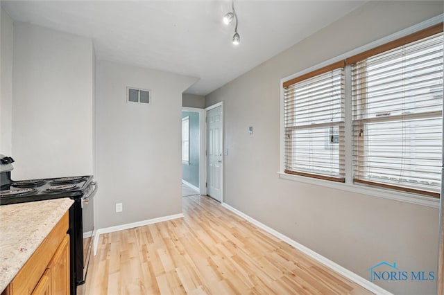 kitchen with black / electric stove and light hardwood / wood-style flooring