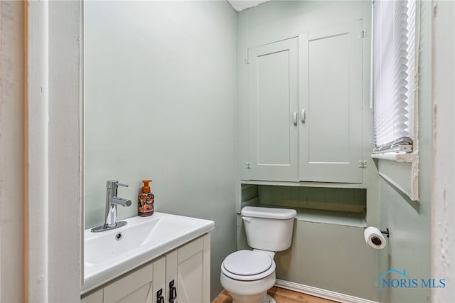 bathroom featuring wood-type flooring, vanity, and toilet