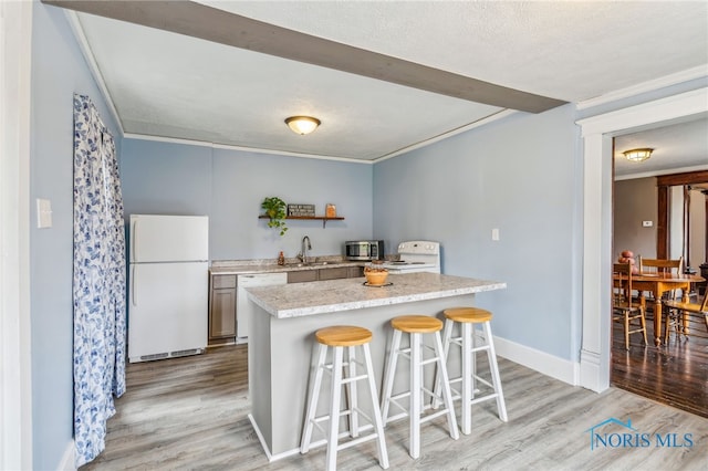 kitchen with sink, stainless steel appliances, a kitchen breakfast bar, light hardwood / wood-style floors, and a textured ceiling