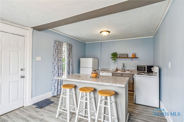 kitchen featuring white appliances, sink, light wood-type flooring, ornamental molding, and a breakfast bar area