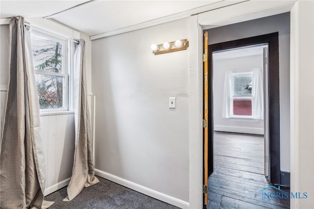 corridor with a wealth of natural light and hardwood / wood-style floors