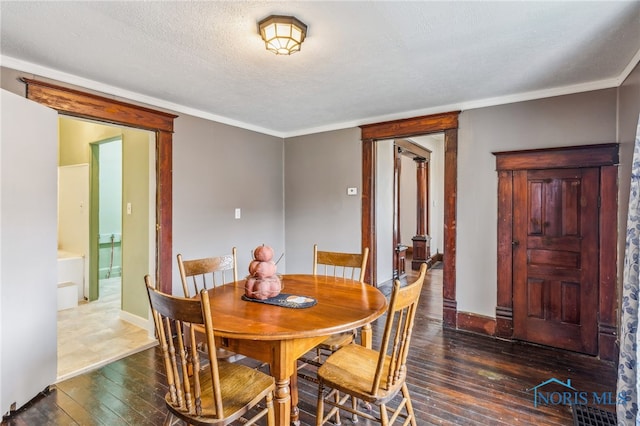 dining area with dark hardwood / wood-style floors, ornamental molding, and a textured ceiling