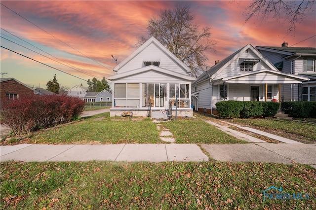 view of front of property with a sunroom and a lawn