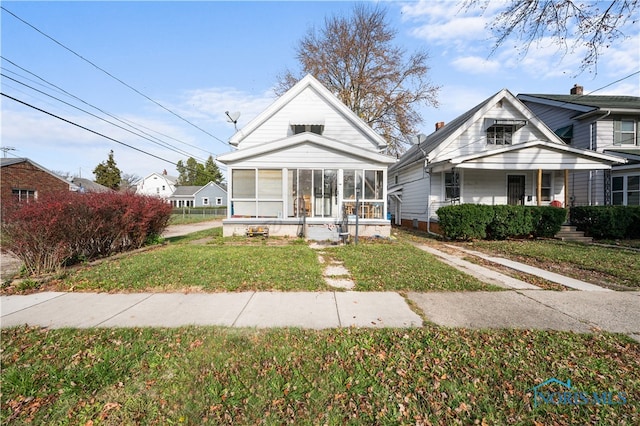 bungalow-style house with a sunroom and a front lawn