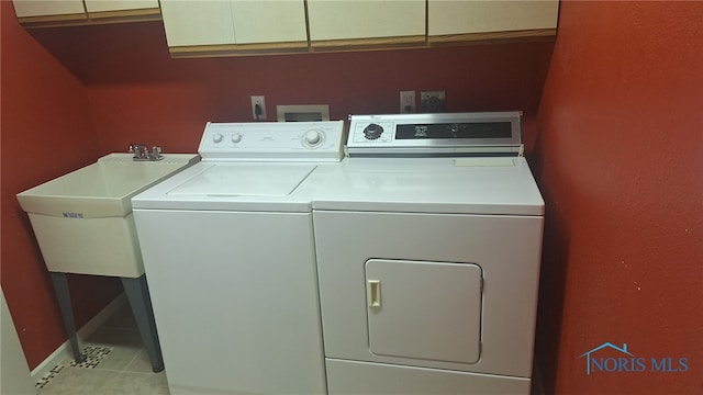 clothes washing area with cabinets, light tile patterned floors, sink, and washing machine and dryer