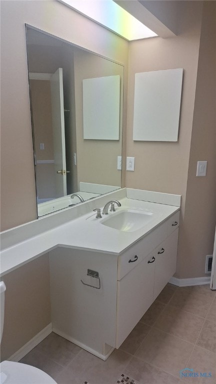 bathroom with toilet, vanity, and tile patterned floors