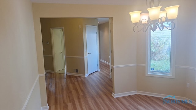 unfurnished dining area featuring a chandelier and wood-type flooring