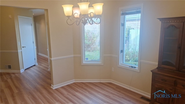 unfurnished dining area with hardwood / wood-style floors and an inviting chandelier