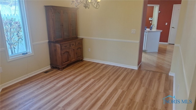 unfurnished dining area featuring light hardwood / wood-style flooring and an inviting chandelier