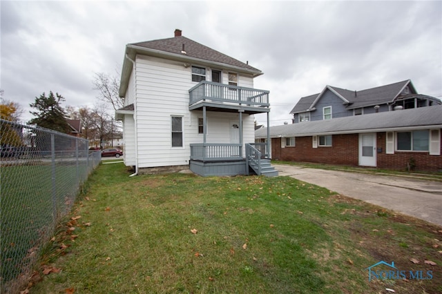 back of house featuring a lawn and a balcony