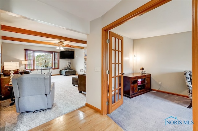 living room with beamed ceiling, light hardwood / wood-style flooring, and ceiling fan