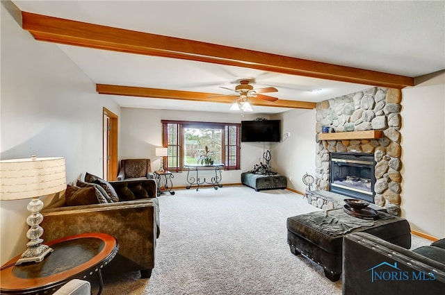 living room with beam ceiling, a stone fireplace, ceiling fan, and carpet