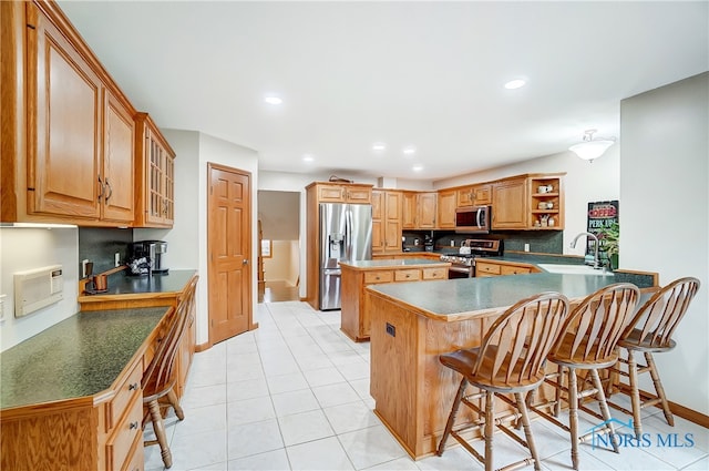 kitchen with a breakfast bar, appliances with stainless steel finishes, kitchen peninsula, and sink