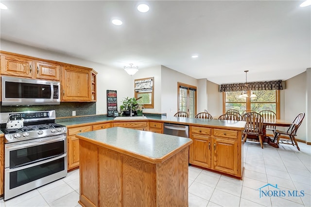 kitchen with kitchen peninsula, pendant lighting, a center island, and stainless steel appliances