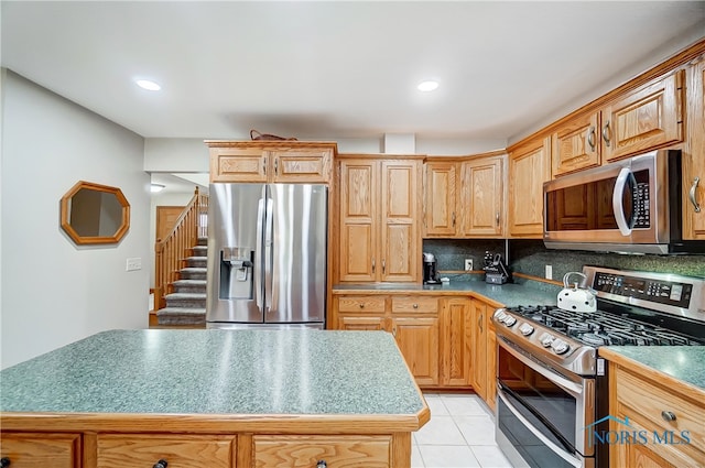 kitchen featuring tasteful backsplash, a center island, light tile patterned floors, and appliances with stainless steel finishes