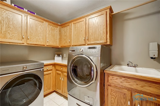 laundry room featuring washer and clothes dryer, sink, light tile patterned floors, and cabinets