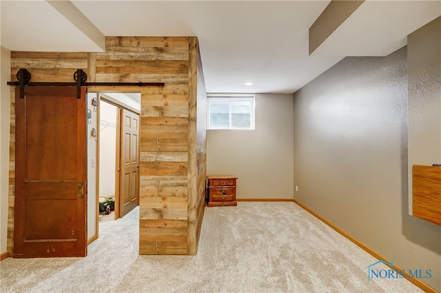 interior space with carpet flooring, a barn door, and wooden walls