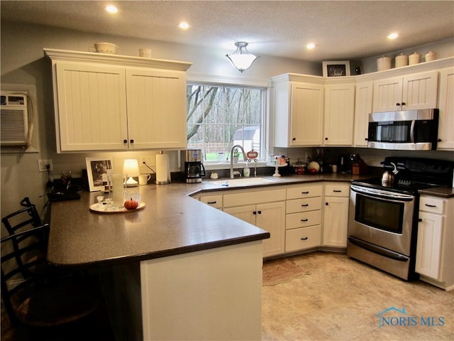 kitchen with white cabinets, sink, a textured ceiling, kitchen peninsula, and stainless steel appliances