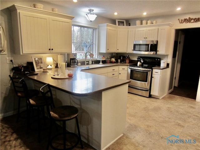 kitchen featuring kitchen peninsula, a breakfast bar, stainless steel appliances, and sink