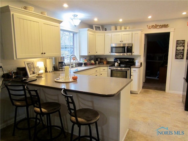 kitchen with a kitchen bar, sink, kitchen peninsula, and stainless steel appliances