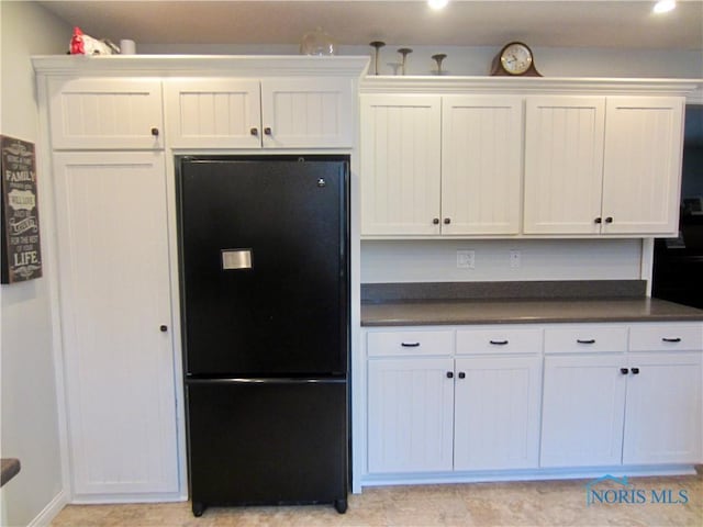 kitchen with white cabinetry and black refrigerator