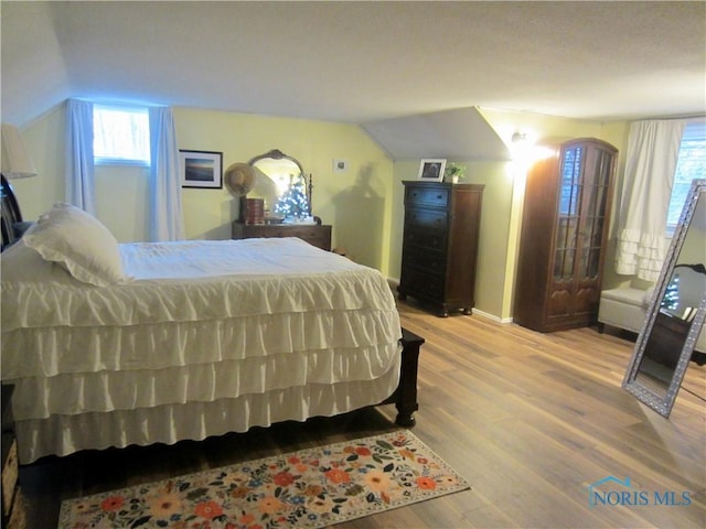 bedroom featuring light hardwood / wood-style floors and vaulted ceiling