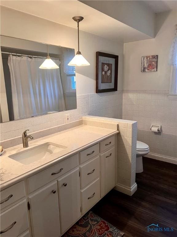 bathroom with vanity, toilet, wood-type flooring, and tile walls