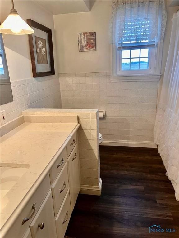 bathroom featuring hardwood / wood-style floors, vanity, toilet, and tile walls