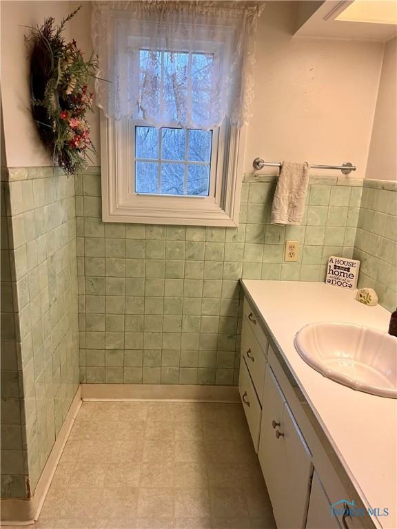 bathroom with vanity and tile walls