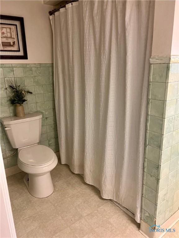 bathroom with toilet and tile walls