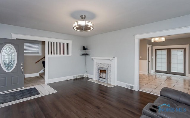 living room with a fireplace, french doors, plenty of natural light, and hardwood / wood-style flooring