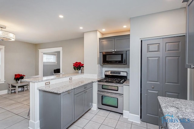 kitchen featuring kitchen peninsula, light stone counters, gray cabinets, and appliances with stainless steel finishes